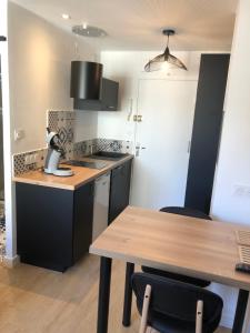 a kitchen with a wooden table and black cabinets at Concarneau centre-ville proche plage in Concarneau