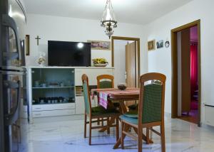 a dining room with a table and chairs and a tv at Apartmani Etica in Postira