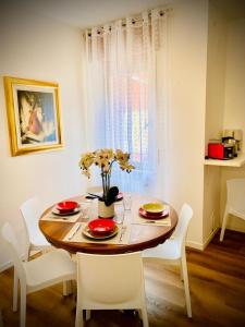 a dining room table with chairs and a table with flowers on it at Mutti Stay apartments in Riva del Garda