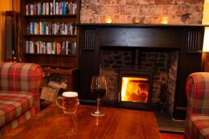 a table with a glass of wine and a fireplace at The Kirkfield Hotel in Newton-le-Willows