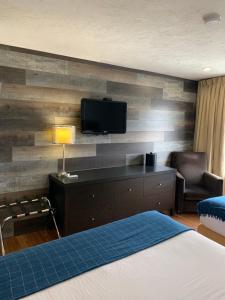 a hotel room with a bed and a tv on a wall at Shores Inn & Hotel in Shediac