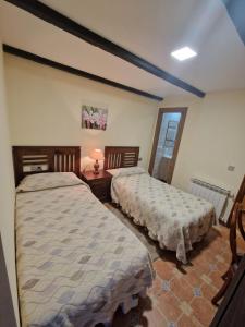 1 dormitorio con 2 camas y mesa con lámpara en Casa Mariana, en Lubián