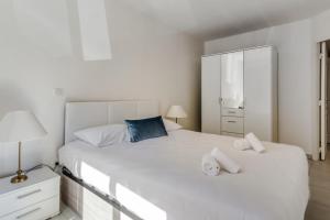 a bedroom with a large white bed and a dresser at Appartement Clap d'Or - Welkeys in Cannes
