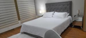 una camera da letto con un grande letto con lenzuola e cuscini bianchi di Casa Boutique HNP a Barrancabermeja