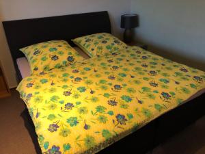 a bed with a yellow bedspread with bees on it at Fewo Geesteblick - Dietmar Strauch in Bremerhaven