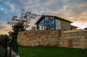 a glass house on top of a stone wall at Casa da Avó Ana Alvão in Bilhó