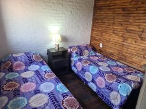 a room with two beds and a table with a lamp at Cabañas Los Ñatos SE RESERVA CON SEÑA !!! in Barra del Chuy