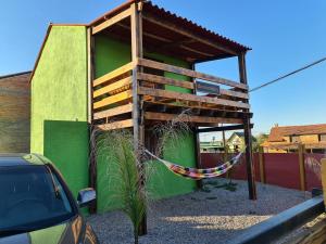 una casa en el árbol con una hamaca unida a un edificio en Cabañas Los Ñatos SE RESERVA CON SEÑA !!!, en Barra del Chuy