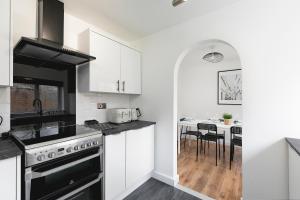 a kitchen with white cabinets and a black stove top oven at Skyvillion - STEVENAGE SPACIOUS & COZY 3Bed House with Parking, Wifi, Garden in Aston End