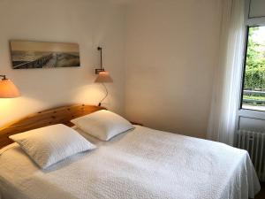 una camera da letto con un letto bianco con due cuscini sopra di Seeschlösschen - Whg 6 nur wenige Schritte zum Strand a Grömitz