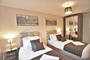 1 dormitorio con 2 camas y espejo en Exec 2Bed 2Bath Serviced Apartment Balcony Parking en Milton Keynes