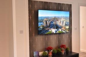 TV de pantalla plana colgada en la pared en Exec 2Bed 2Bath Serviced Apartment Balcony Parking, en Milton Keynes