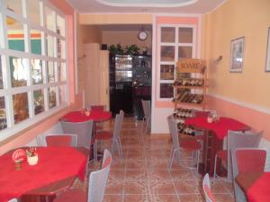 Penzion Laguna في Kunratice: مطعم بطاولات حمراء وكراسي ونافذة