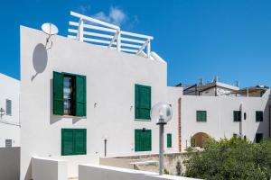 un edificio blanco con persianas verdes. en Appartamento SEGESTA, en Favignana