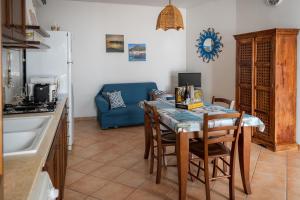 una cucina con tavolo, sedie e divano blu di Appartamento SEGESTA a Favignana