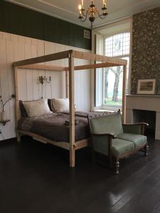 a bedroom with a canopy bed and a chair at De kastanjehof 31 in Beerta