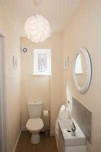 een badkamer met een toilet, een wastafel en een spiegel bij Lovely 2-bedroom Seaside Retreat with Free Parking in Great Yarmouth
