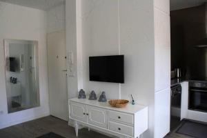 a white living room with a television on a wall at Casa Onda Spot in Nazaré