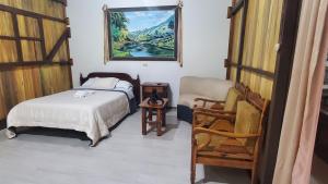 a bedroom with a bed and a chair at CASA BLANCA HORTENCIA in Sucúa