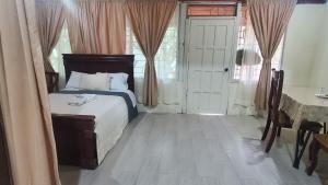 um quarto com uma cama, uma mesa e janelas em CASA BLANCA HORTENCIA em Sucúa