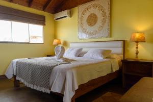 a bedroom with a bed with a white bedspread and two windows at Wallac Bungalows Canoas de Punta Sal in Canoas De Punta Sal