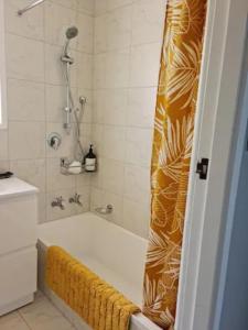 een badkamer met een bad en een douche met een geel douchegordijn bij Gondola Views on Mallard in Rotorua