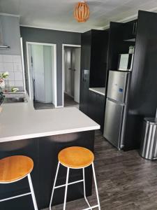 a kitchen with two stools and a counter and a refrigerator at Gondola Views on Mallard in Rotorua