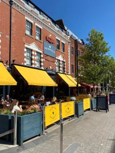 a street with people sitting at tables with yellow umbrellas at The White Star Tavern in Southampton