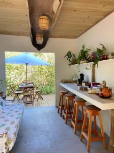 eine Küche mit einem Tisch, Stühlen und einem Sonnenschirm in der Unterkunft Beco do Pescador in Caraíva