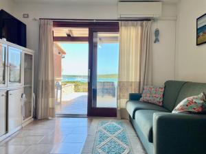 a living room with a couch and a sliding glass door at Casa Leo - Villaggio Baia De Bahas in Golfo Aranci