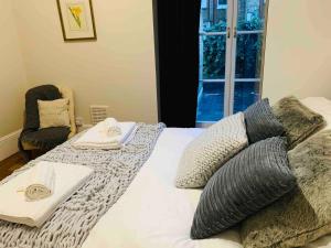 sypialnia z łóżkiem z poduszkami i oknem w obiekcie Luxury Fulham Flat with 5* touches nr River Thames w Londynie