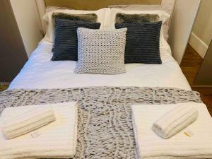 łóżko z białymi kocami i poduszkami w obiekcie Luxury Fulham Flat with 5* touches nr River Thames w Londynie