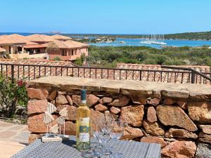 a bottle of wine sitting on a table with wine glasses at Casa Leo - Villaggio Baia De Bahas in Golfo Aranci