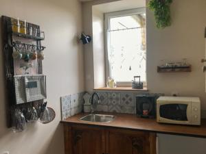 a kitchen with a sink and a microwave on a counter at "La chambre des TISSERANDS" in Ménil-Hubert-sur-Orne +13 photos