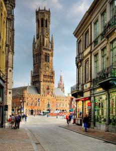 a large building with a clock tower in a city at Dukes' Arches Brugge Adults only in Bruges