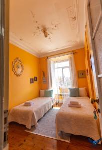 due letti in una stanza con pareti gialle di Lisbon Angels Hostel a Lisbona
