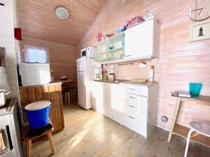 eine Küche mit einem weißen Kühlschrank und einer Holzwand in der Unterkunft Loistava Aurinkoranta Mökki in Ähtäri