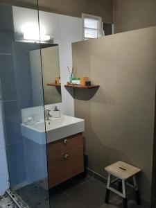 uma casa de banho com um lavatório, um espelho e um banco em Alyzes Diamant em Le Diamant