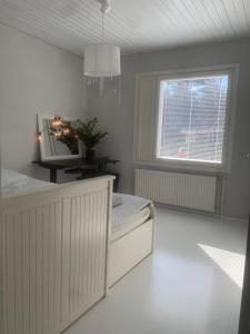a white bedroom with a bed and a window at Omakotitalo rauhallisella sijainnilla lähellä keskustaa Maksuton pysäköinti ja puusauna in Hämeenlinna