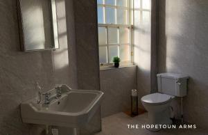 łazienka z umywalką, toaletą i oknem w obiekcie The Hopetoun Arms Hotel w mieście Leadhills