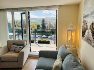 a living room with a couch and chairs and a large window at Riverside View Penthouse in Balloch, Loch Lomond in Balloch