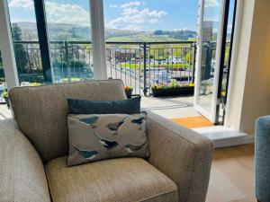 a living room with a chair with a pillow with dolphins on it at Riverside View Penthouse in Balloch, Loch Lomond in Balloch