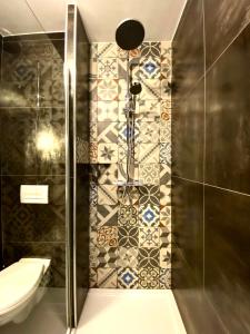 uma casa de banho com chuveiro, WC e azulejos em Drissia&Othman Bella Noche em Carcassonne