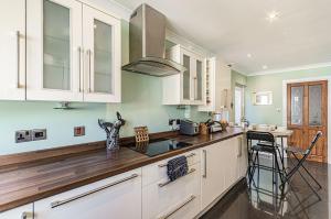 a kitchen with white cabinets and a wooden counter top at Ty'r Ystrad in Kidwelly