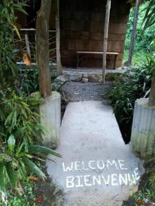 un cartel de bienvenida en un jardín con un banco en Natty Tropical Valley, en Roseau