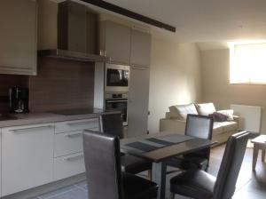 a kitchen and living room with a table and a couch at Trilogie Appartementen & Gasterij in Kemmel