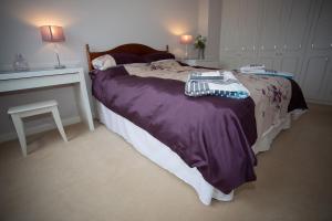 a bedroom with a bed with purple blanket and a table at Henbury Hide in Corfe Mullen