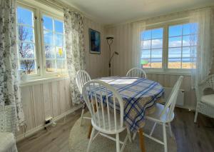 a dining room with a table and chairs and windows at Fishermans View in Alstad