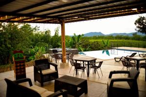 Un patio con mesas y sillas junto a una piscina. en ORIGEN FINCA HOTEL, en Quimbaya
