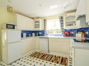 GaytonにあるThe Granary Cottageの白いキャビネットとチェッカーフロア付きのキッチン